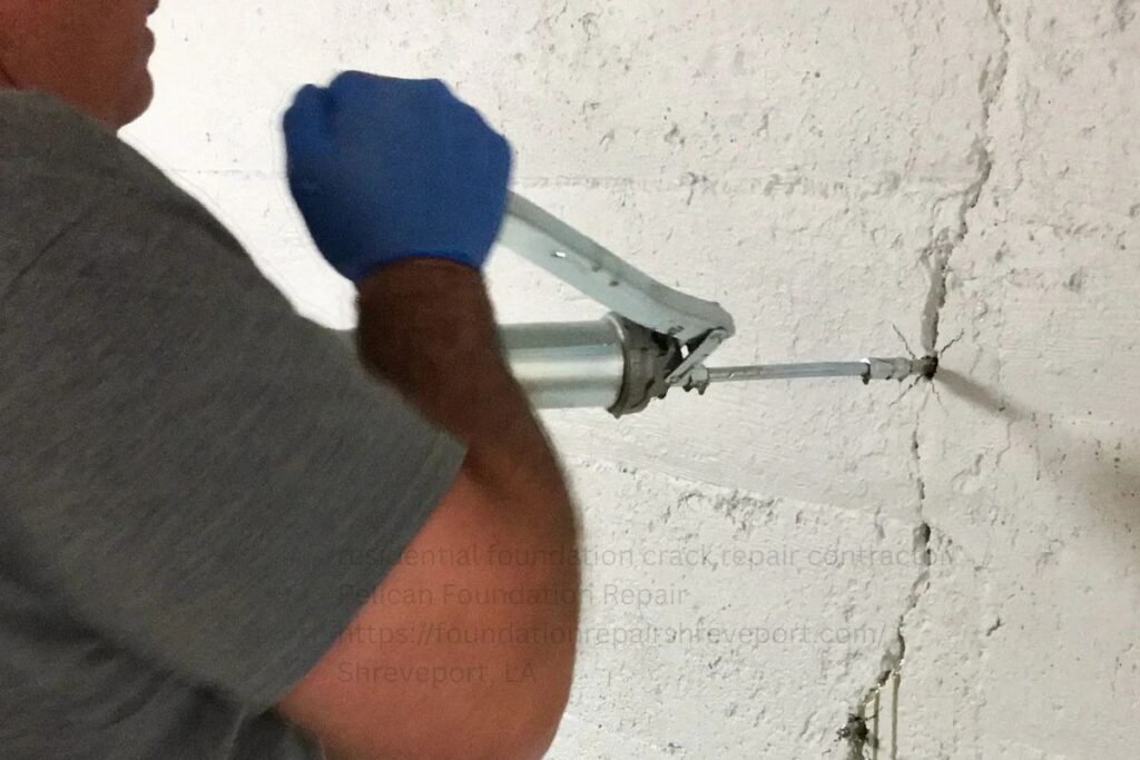 Technician injecting epoxy into a foundation wall crack