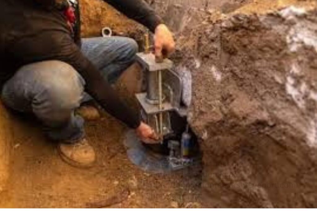 Worker installing a steel pier bracket on a house foundation